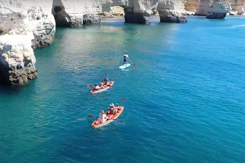 Tres kayaks sobre un mar tranquilo con acantilados rocosos al fondo. 2
