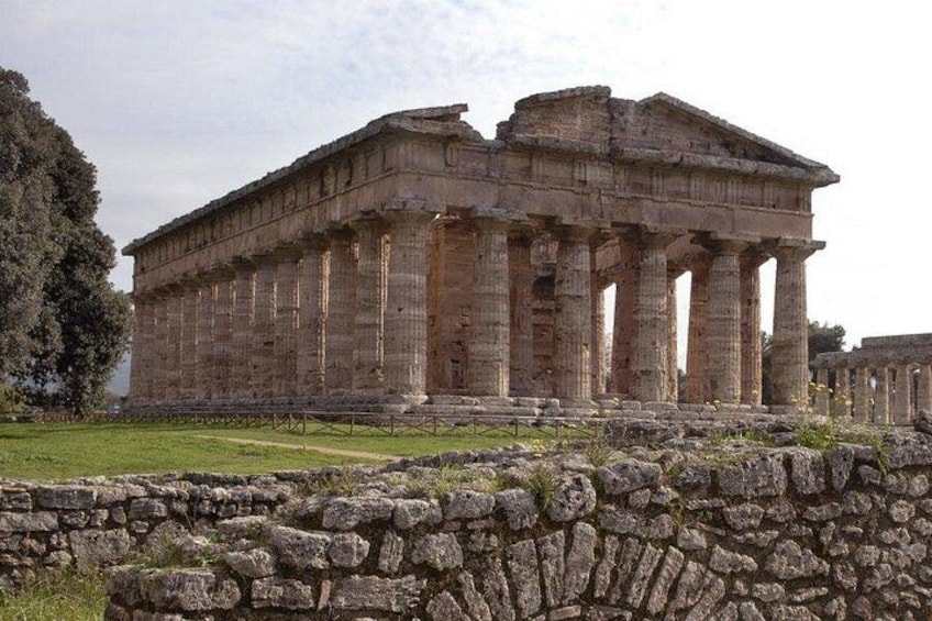Un antico tempio greco con colonne e un muro in pietra sullo sfondo. 4