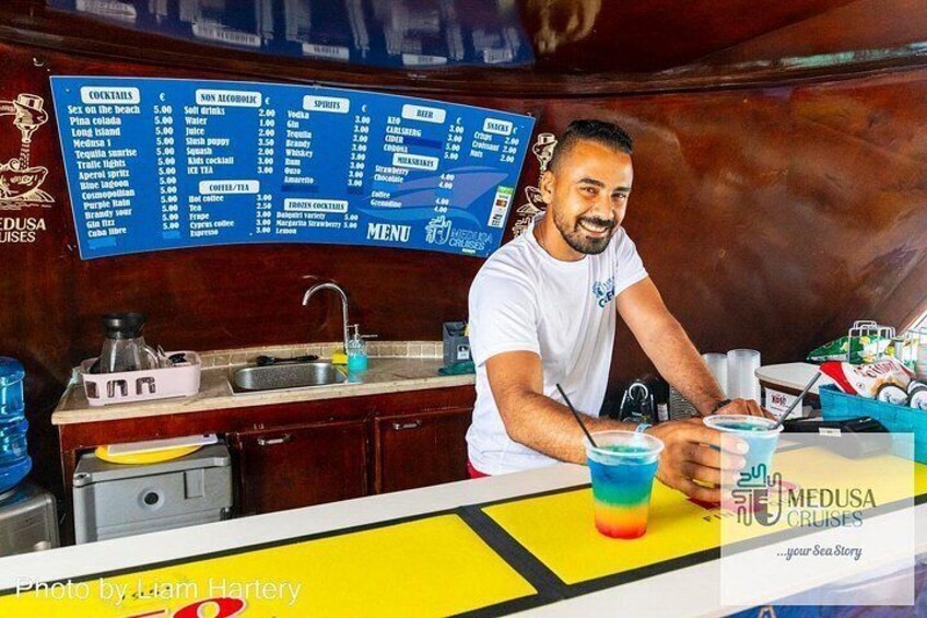 Una persona preparando bebidas en un bar con un menú colgado. 2