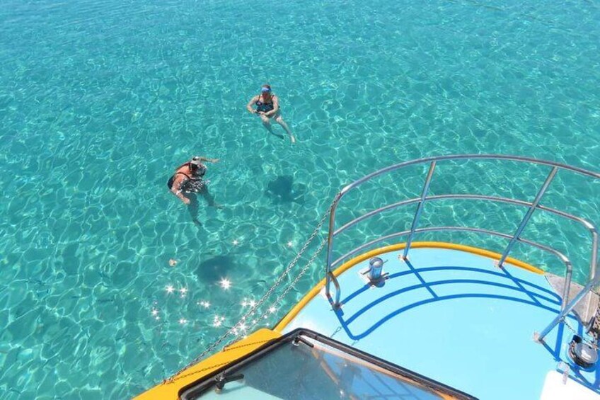 A boat with two people snorkeling in clear blue water. 2