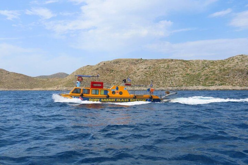 A yellow boat named 'DORY SAFARI GLASS' on the water with a rocky landscape in the background. 3