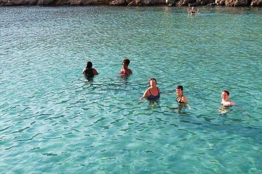 A group of people swimming in a clear blue body of water. 5