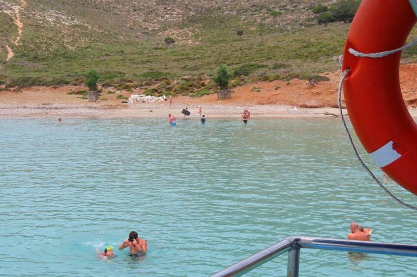 A swimming pool with people in the water, a lifebuoy, and a beach in the background. 4