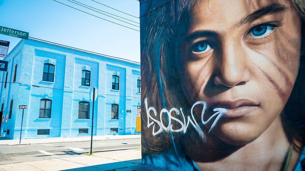 Un bâtiment bleu avec une plaque de rue indiquant « Jefferson Street » et une grande fresque sur laquelle on peut lire le mot « SOS ». 3
