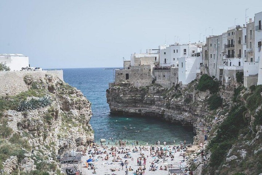 A coastal town with white buildings, a rocky cliff, and a beach. 3