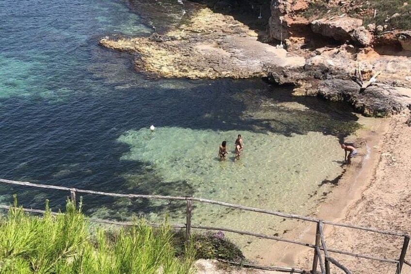 Una zona costera con aguas cristalinas, formaciones rocosas y una playa arenosa. 4