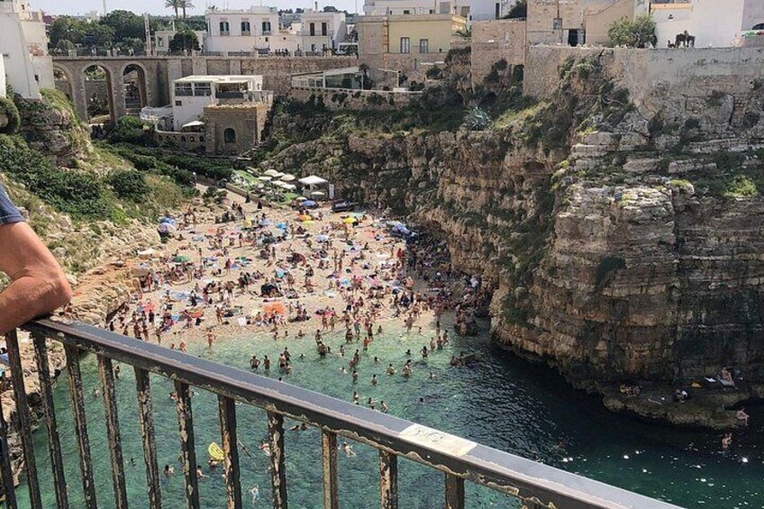 A crowded beach with rocky cliffs and buildings in the background. 4