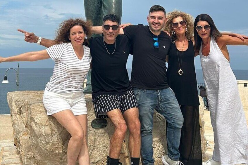 A group of people posing by a rocky seaside with the ocean in the background. 4