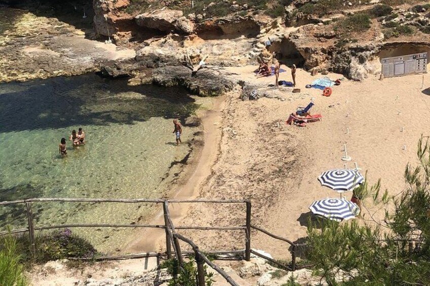 Una playa con agua cristalina, formaciones rocosas y gente tomando el sol. 5