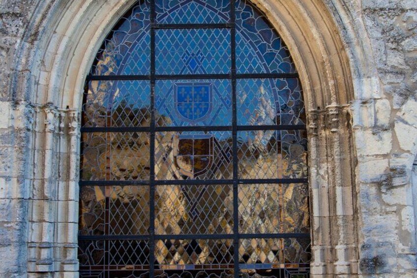 Un arco de piedra con un ventanal de vitral que muestra un escudo de armas azul. 5