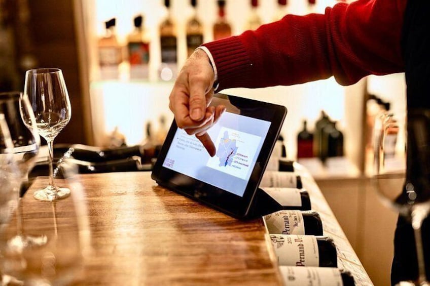 A person using a tablet at a bar with a wine glass and bottles in the background. 3