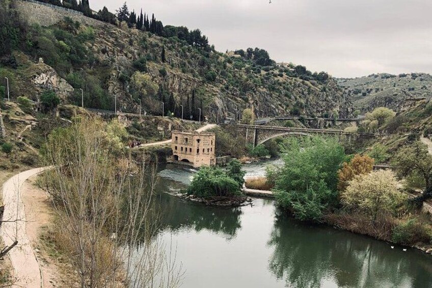 Un fiume con un ponte, un piccolo edificio e un sentiero lungo la riva. 3
