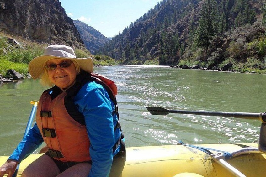 A person in a yellow raft on a river surrounded by mountains. 4
