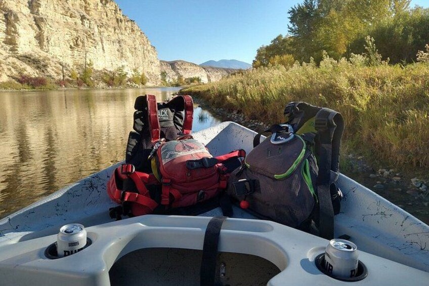 A boat with a person lying on the back, a red life jacket, and a green backpack. 3