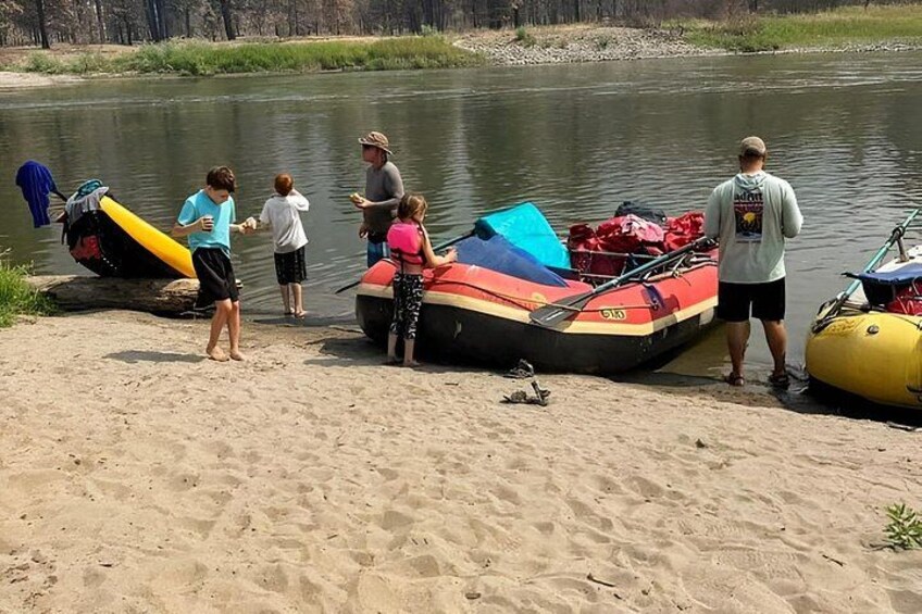 People near a river with boats and a kayak. 2