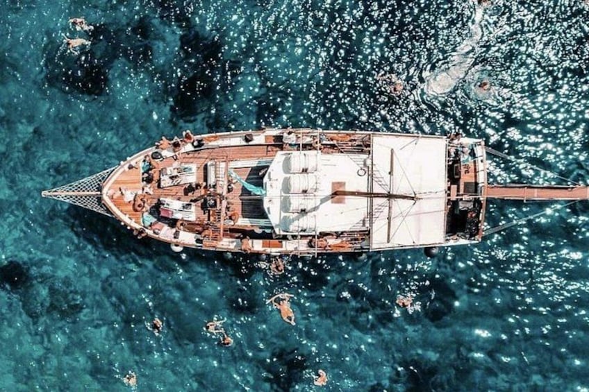 A boat with a cabin and deck chairs, floating on clear blue water. 1