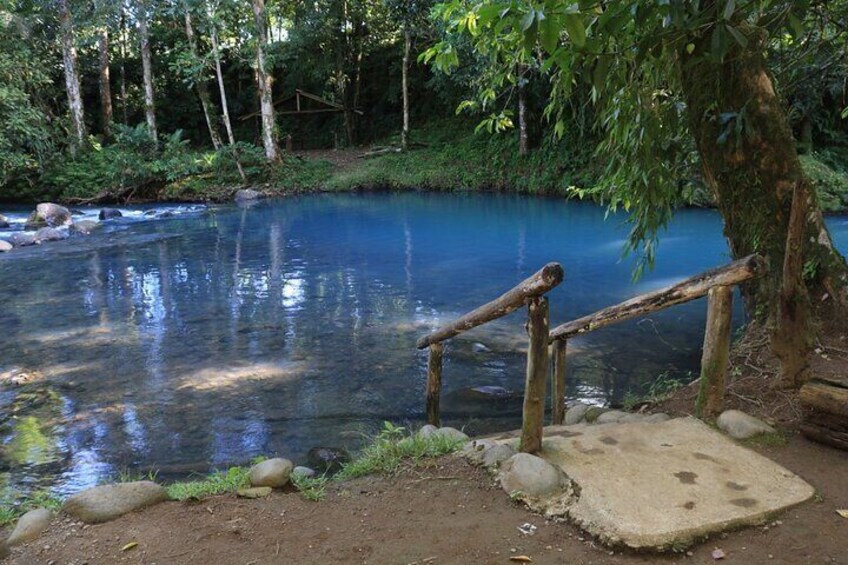 A clear blue stream with a wooden bridge and a concrete platform. 1