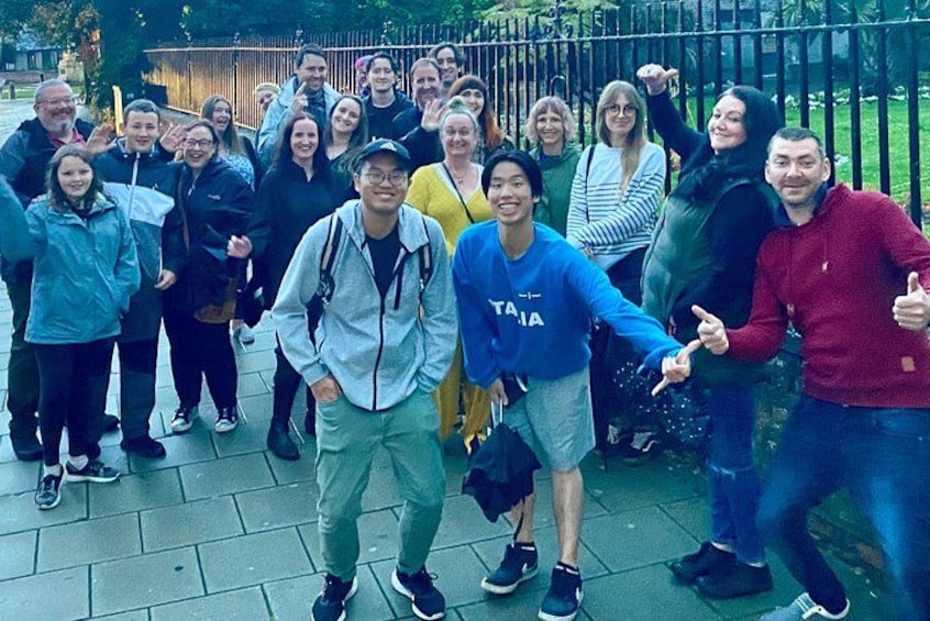 A group of people standing on a paved area with a metal fence in the background. 3