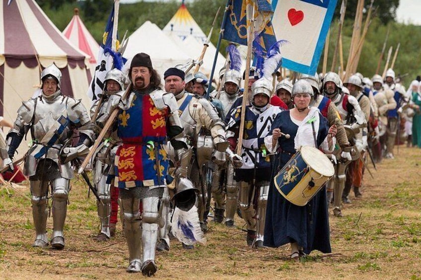 A group of people in medieval armor marching with flags and drums. 1