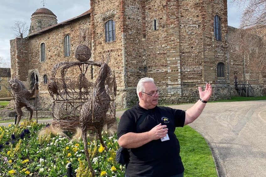 A man standing in front of a historic stone building with a sculpture of a horse and rider. 5