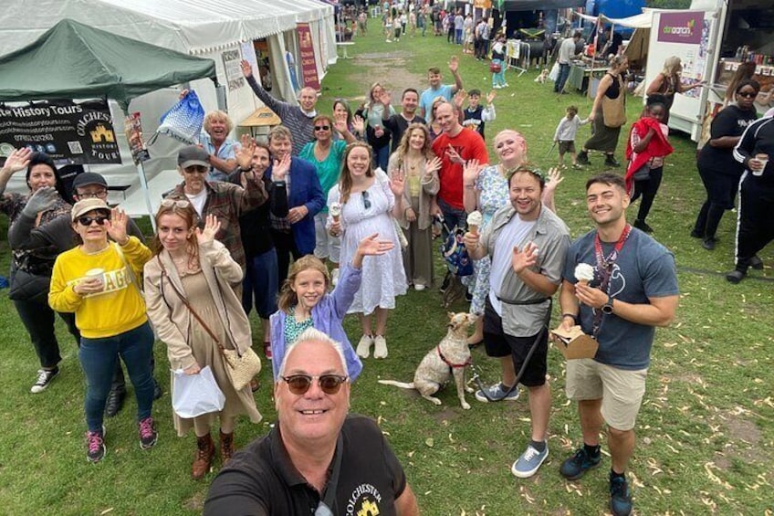 A group of people at an outdoor event with tents and banners in the background. 2