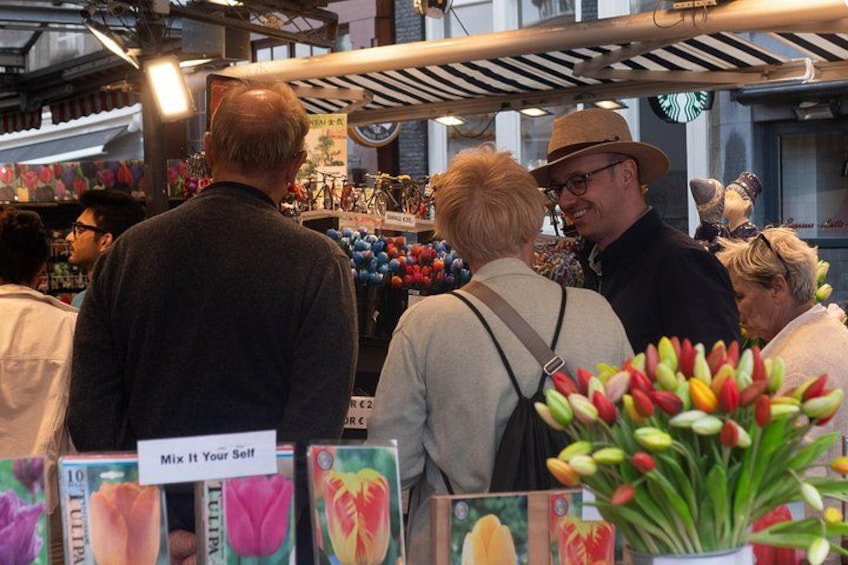 En marknadsplats där folk går runt och tittar, en skylt med texten ”Blanda själv”, och ett stånd med tulpaner. 4