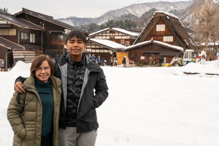 Un paysage hivernal enneigé avec des bâtiments traditionnels en bois et une chaîne de montagnes en arrière-plan. 4