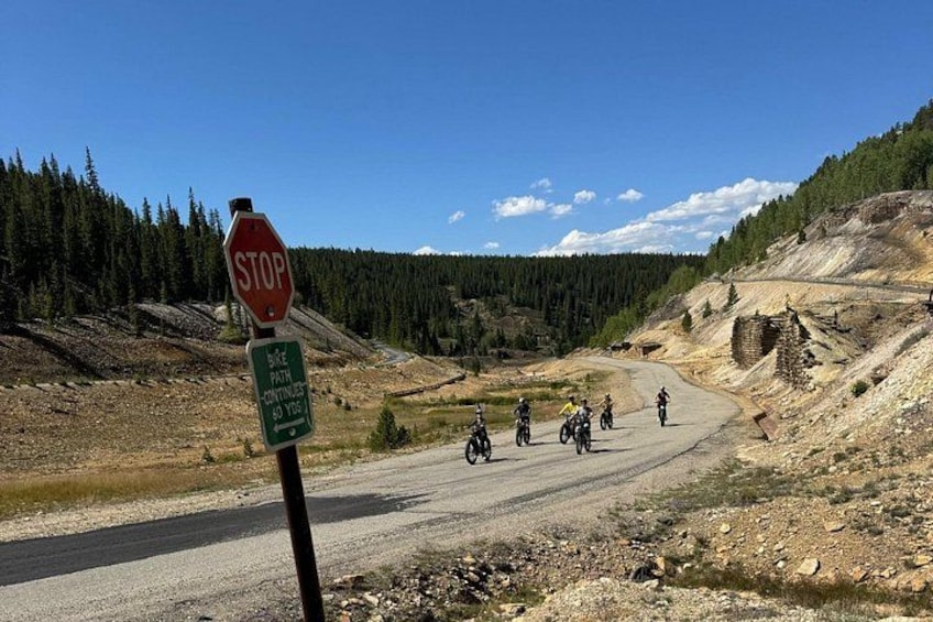 A stop sign, a bike path sign, and a group of motorcyclists on a winding road. 3