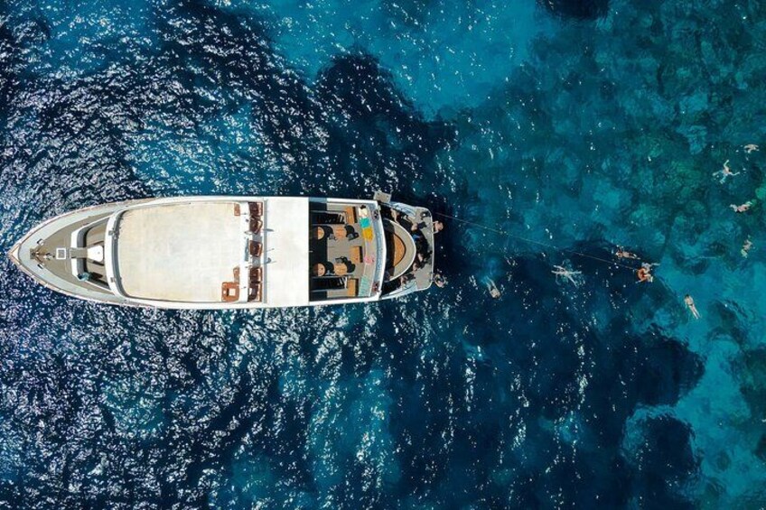 Un barco fondeado en aguas azul turquesa con formaciones rocosas cercanas. 3