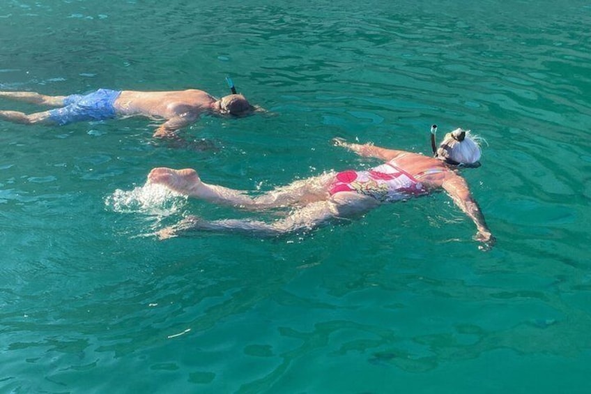 Two people swimming in clear blue water. 4