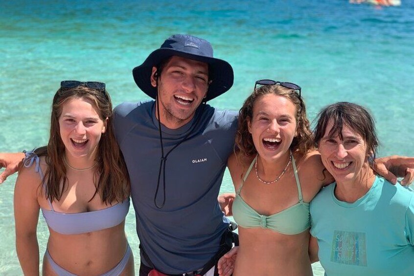 Un groupe de personnes se trouve sur une plage, dans un endroit où l’eau est d’un bleu turquoise limpide. 4