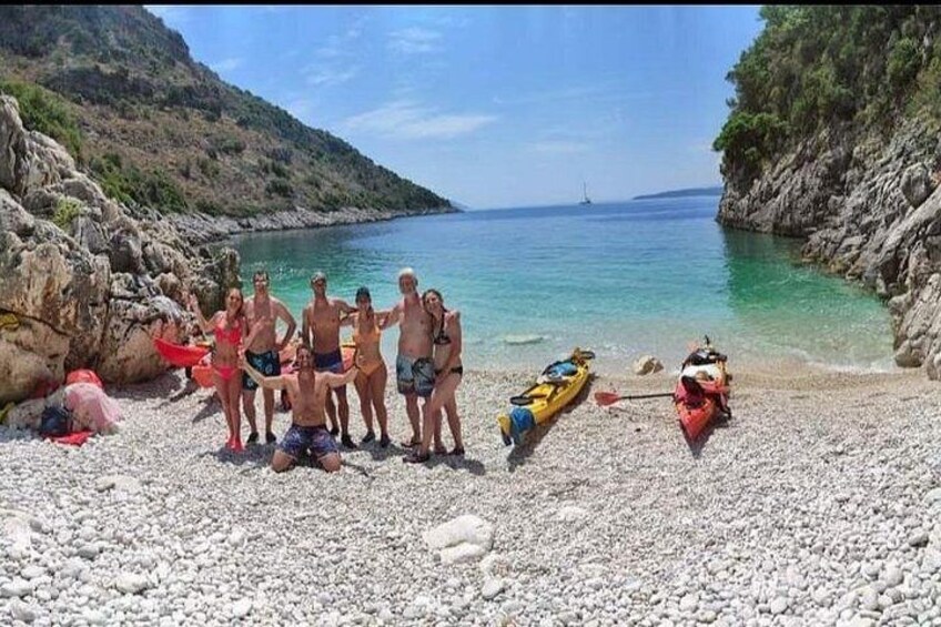 Eine Gruppe von Menschen an einem Kiesstrand mit Kajaks. 2