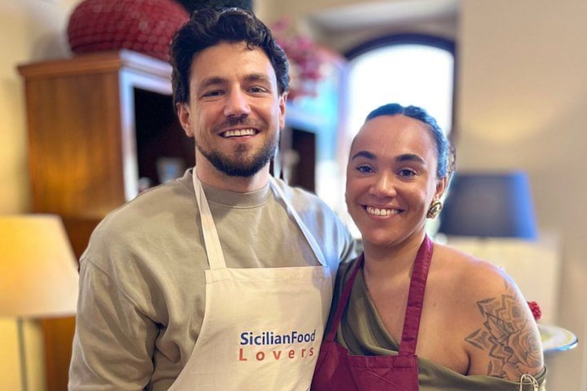 A person wearing a white apron with 'Sicilian Food Lovers' printed on it. 3