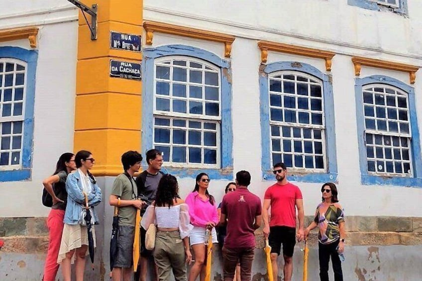 A group of people standing in front of a building with blue and white walls and arched windows. 5