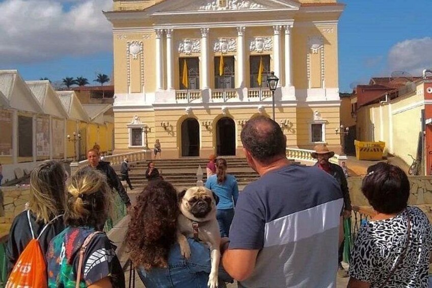 A group of people gathered in front of a historic building with columns and a balcony. 2