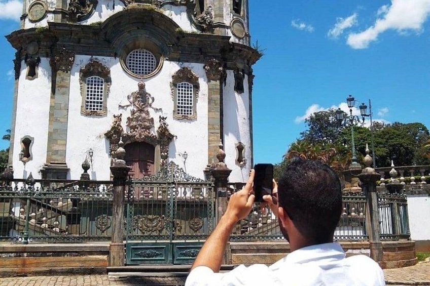 A historic building with ornate architecture, a gated entrance, and a person taking a photo. 2