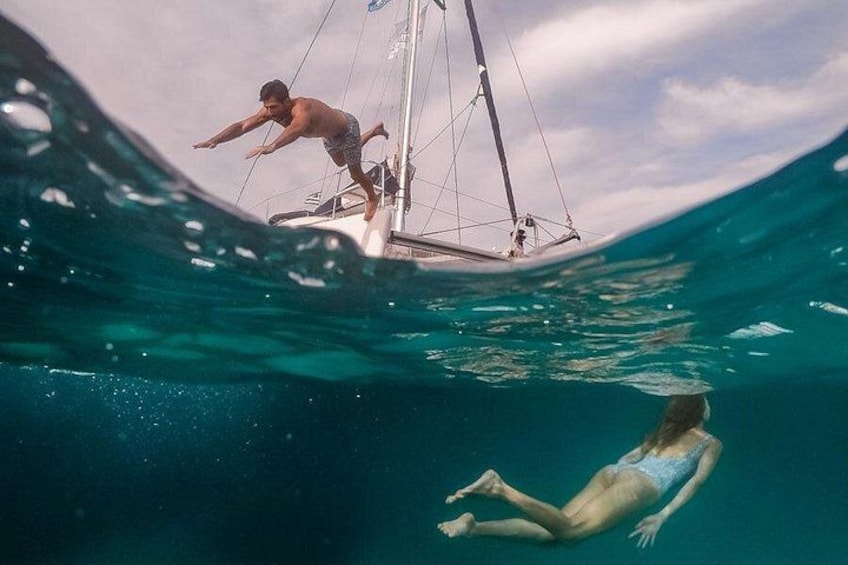 En segelbåt på vattnet med en person som simmar under den. 1