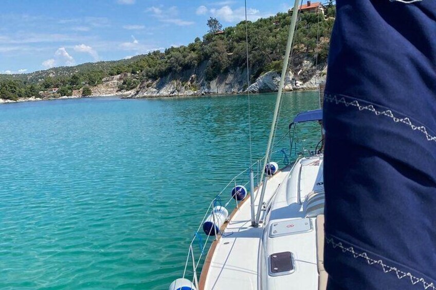 Een boot op turquoise water, met een rotsachtige kustlijn en begroeiing op de achtergrond. 5
