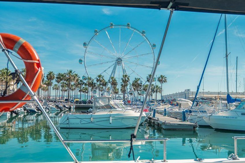 A marina with boats, a Ferris wheel, and palm trees. 5