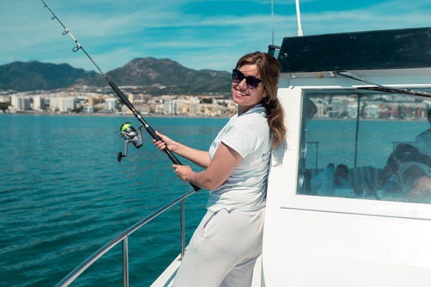 A person fishing on a boat with a cityscape in the background. 4