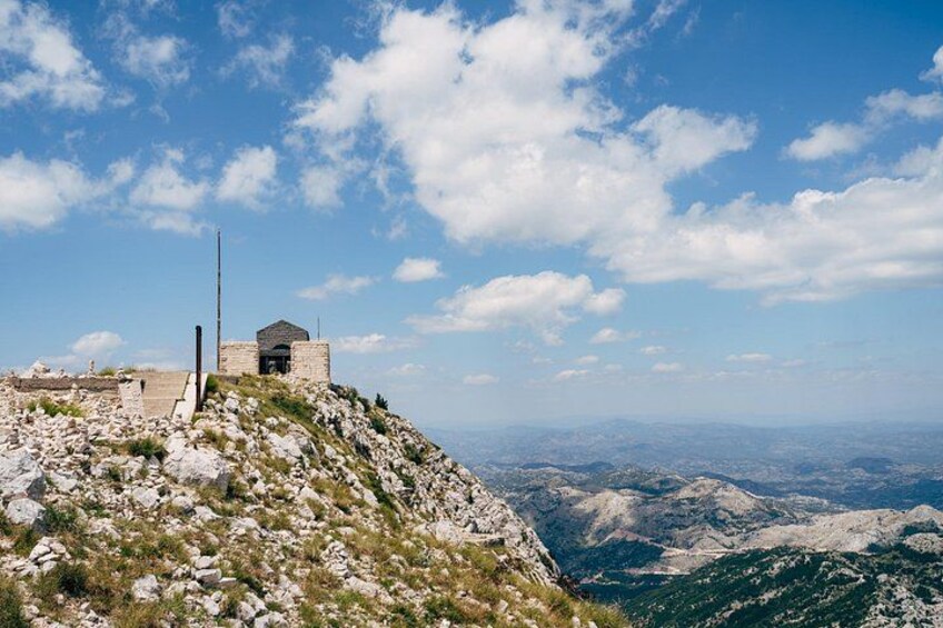 A rocky hill with a small stone building and a flagpole. 4
