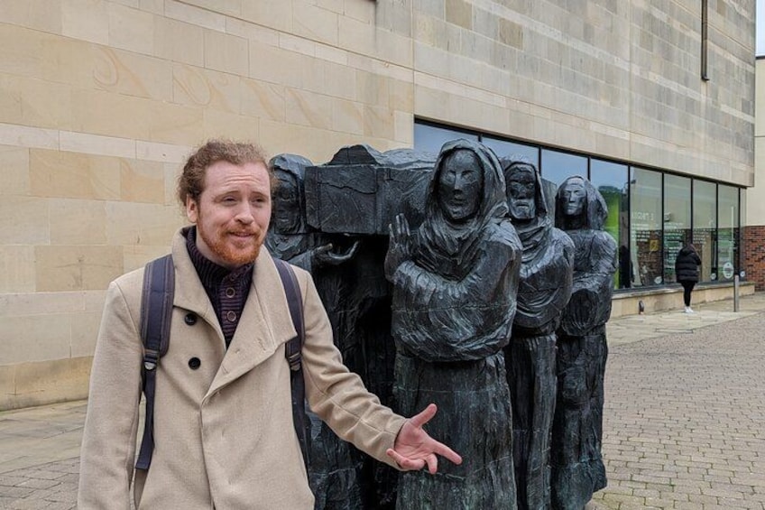 A person standing in front of a sculpture of figures. 4