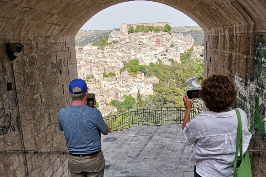 Deux personnes prennent des photos d’une ville historique depuis une arche en pierre. 3