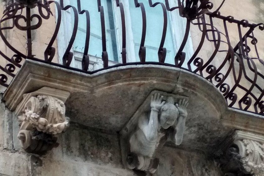 Un garde-corps de balcon en fer forgé, orné de motifs complexes, et une balustrade en pierre agrémentée de sculptures. 5