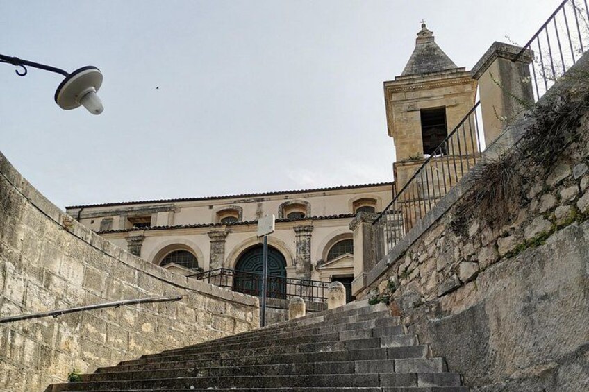 A stone staircase leading to a building with arched windows and a bell tower. 2