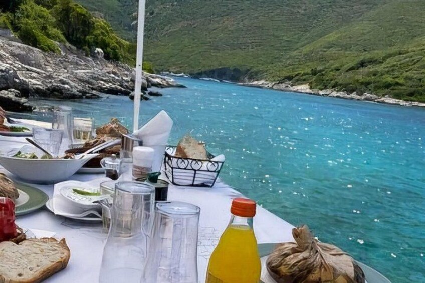Un tavolo apparecchiato con cibo e bevande in riva all'acqua. 2