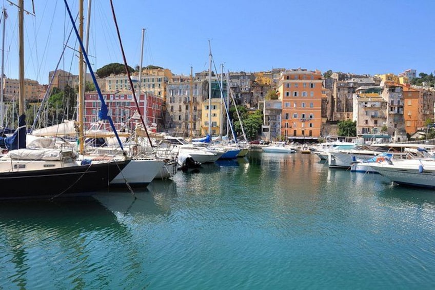 A marina with boats docked, a clear blue sky, and colorful buildings in the background. 5
