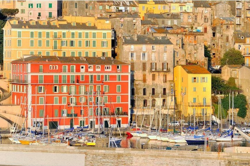 A coastal town with colorful buildings, a marina with boats, and a hilly backdrop. 4