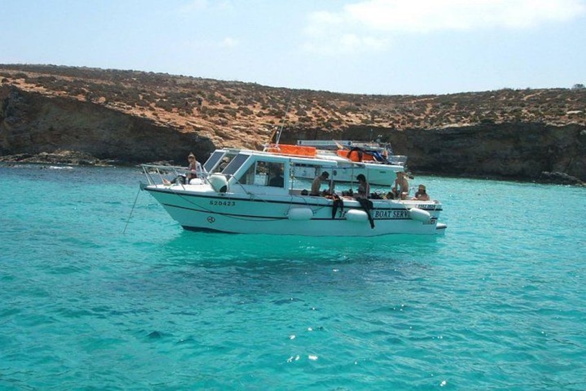 A boat with the number 620423 on the side, floating on turquoise water with a rocky coastline in the background. 4