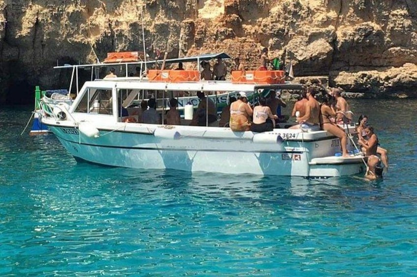 A boat with people on it near rocky cliffs. 3